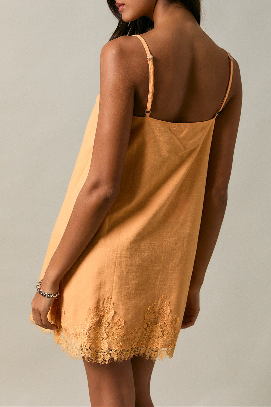 Woman wearing a mustard yellow slip dress against a neutral background