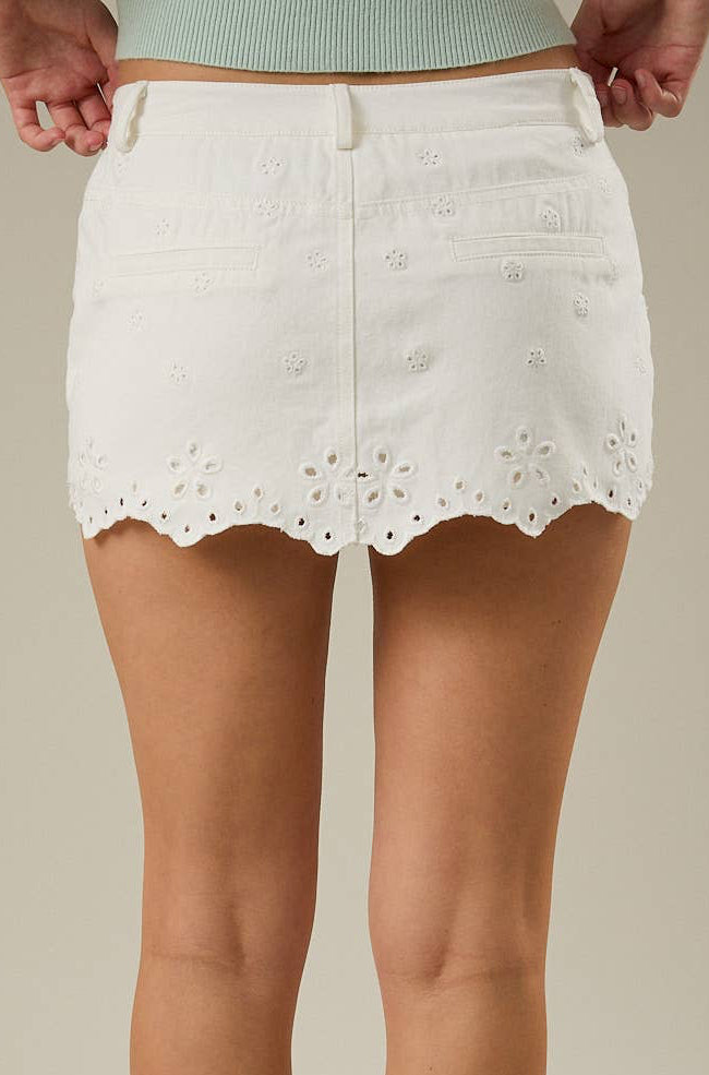White lace skirt worn by a person on a beige background