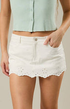 Woman wearing a light green sleeveless top and white shorts on a beige background