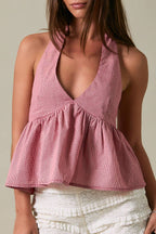 Woman wearing a pink halter top and white shorts against a beige background