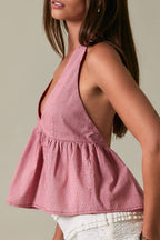 Woman wearing a red top and white shorts against a beige background