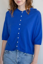 Woman wearing a blue shirt with white buttons against a plain background