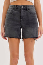 Person wearing black denim shorts on a white background