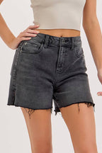 Woman wearing a beige strapless top and black denim shorts on a white background