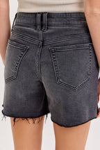 Black denim shorts worn by a person on a white background