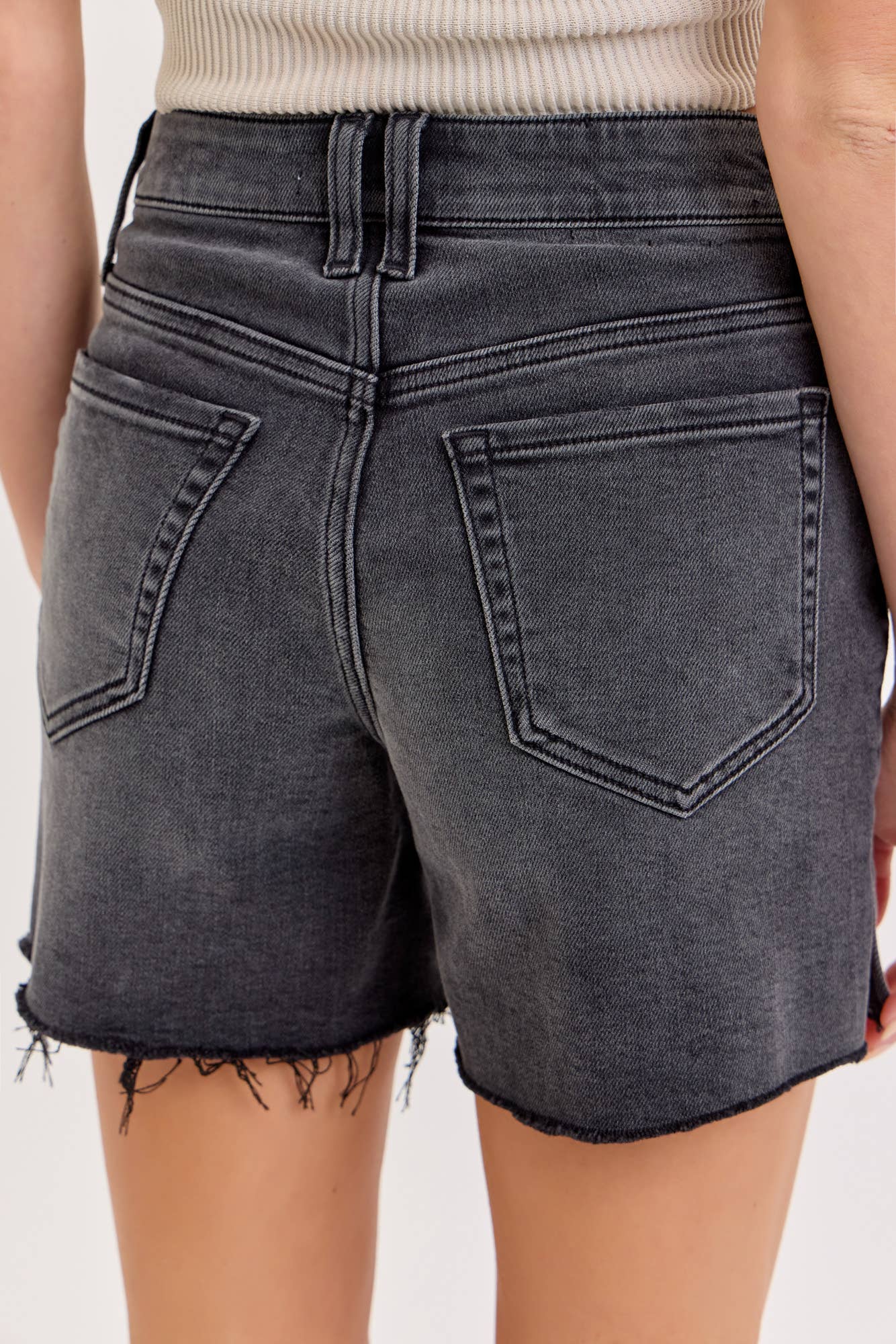 Black denim shorts worn by a person on a white background