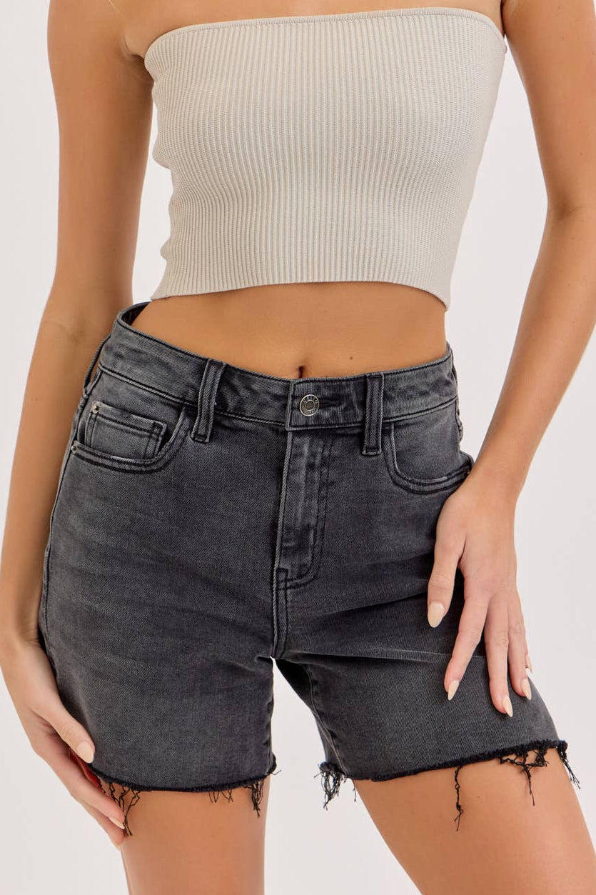 Woman wearing a beige strapless top and black denim shorts on a white background