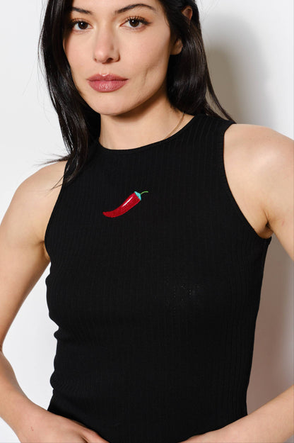 Woman wearing a black sleeveless top with a red chili pepper design on a white background