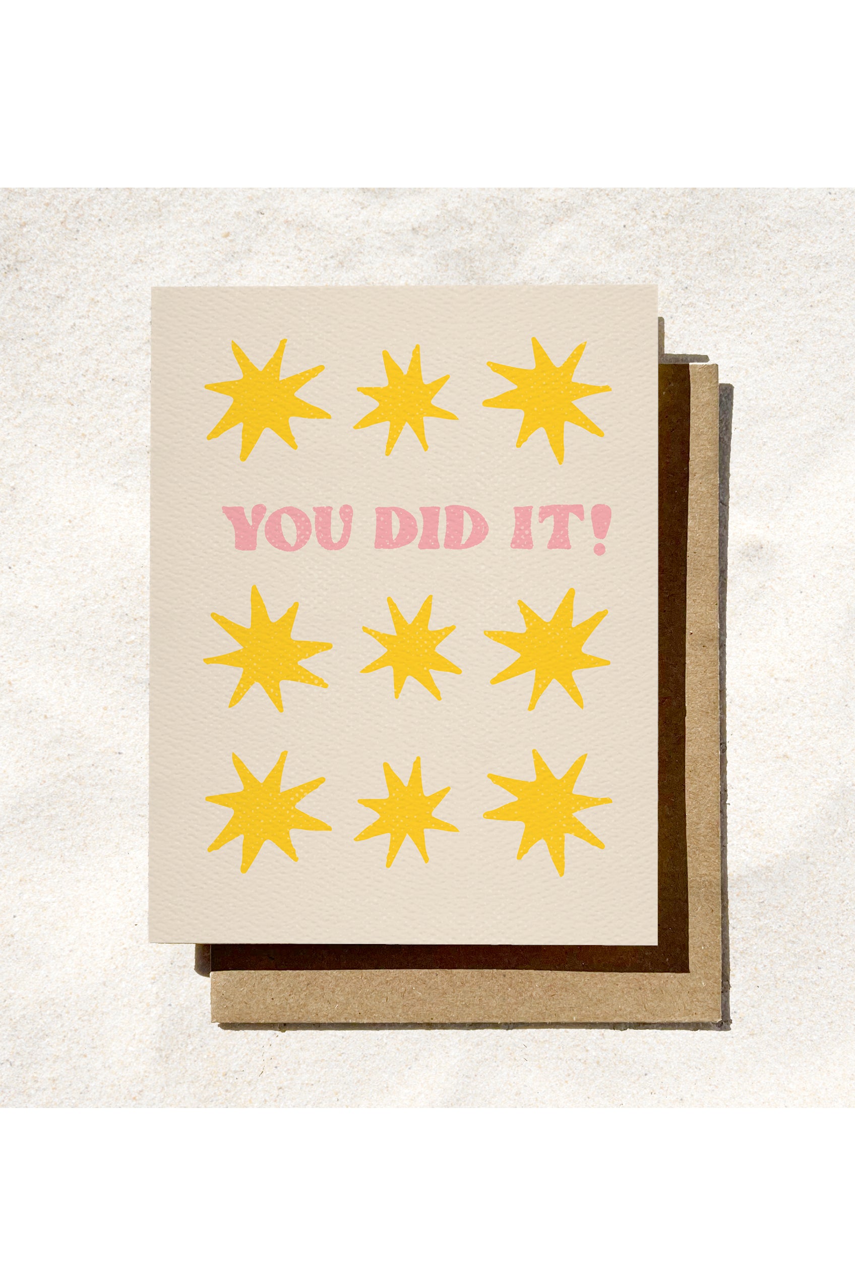 Greeting card with yellow stars and 'YOU DID IT!' text on a textured surface