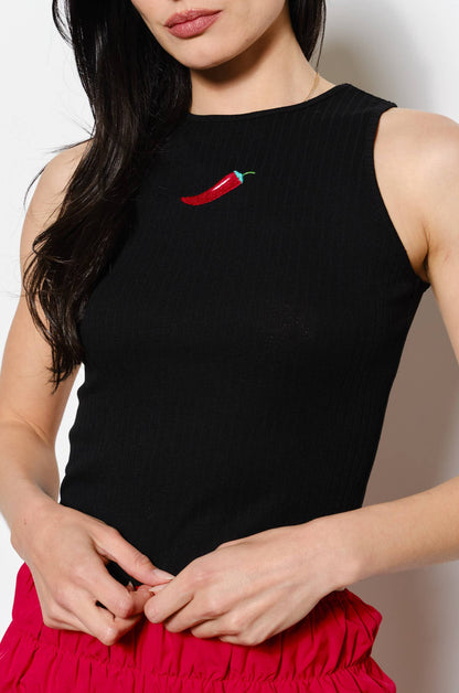 Woman wearing a black sleeveless top with a red pepper design and a red skirt against a white background