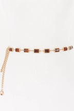 Gold anklet with brown square stones on a light gray background