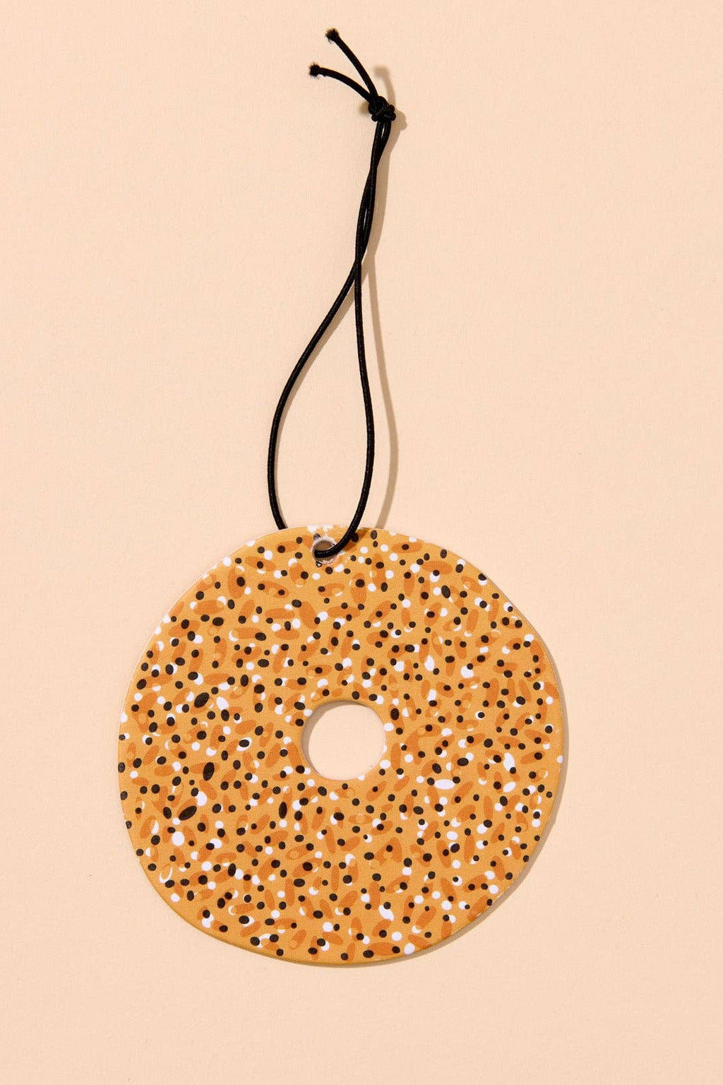 Round textured yellow object with a black string on a beige background