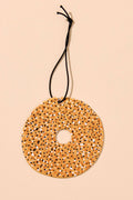 Round textured yellow object with a black string on a beige background