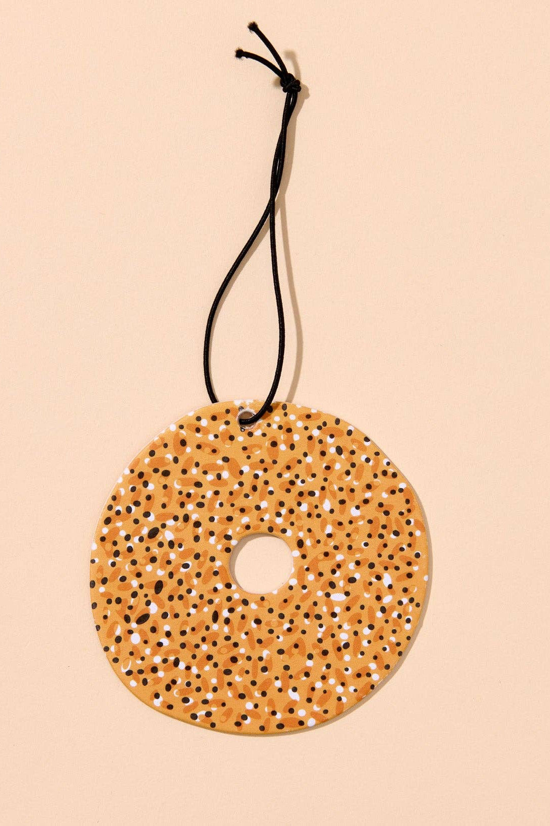 Round textured yellow object with a black string on a beige background