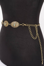 An antique bronze belt with three oval decorative medallions and turquoise accents, displayed on a black mannequin torso against a white background.