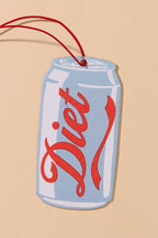 A novelty Diet soda can-shaped wall hanging or ornament with a red hanging string, shown on a solid beige background.