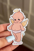 Hand holding a sticker of an angel baby with a blurred background
