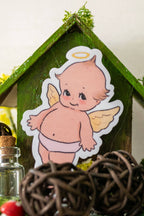 Decorative scene with a small house, angel figurine, and decorative elements on a white background