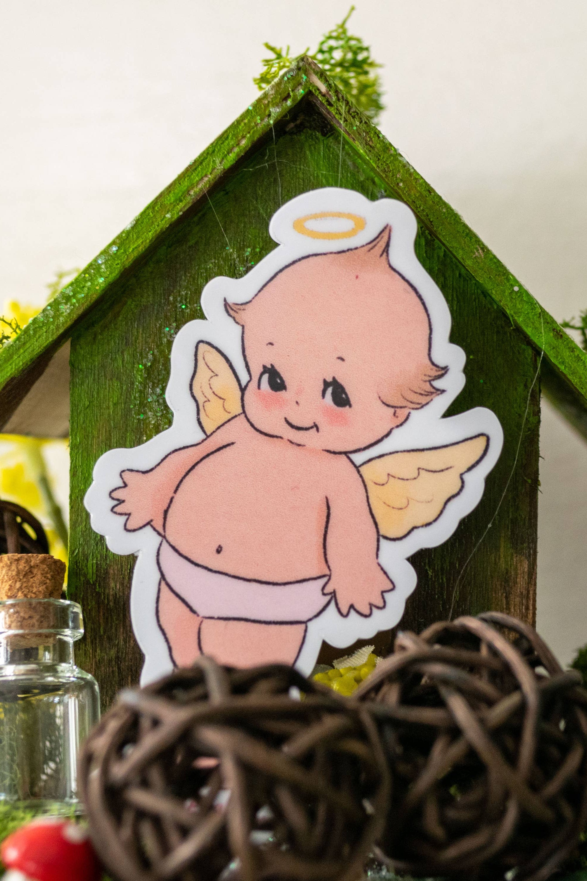 Decorative scene with a small house, angel figurine, and decorative elements on a white background