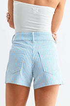 Woman wearing light blue striped shorts and a white strapless top on a white background