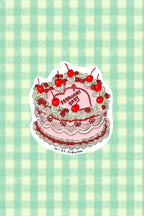 Sticker of a birthday cake with red cherries on a green and white checkered background