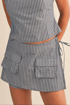 Woman wearing a gray striped skort with front pocket on a beige background