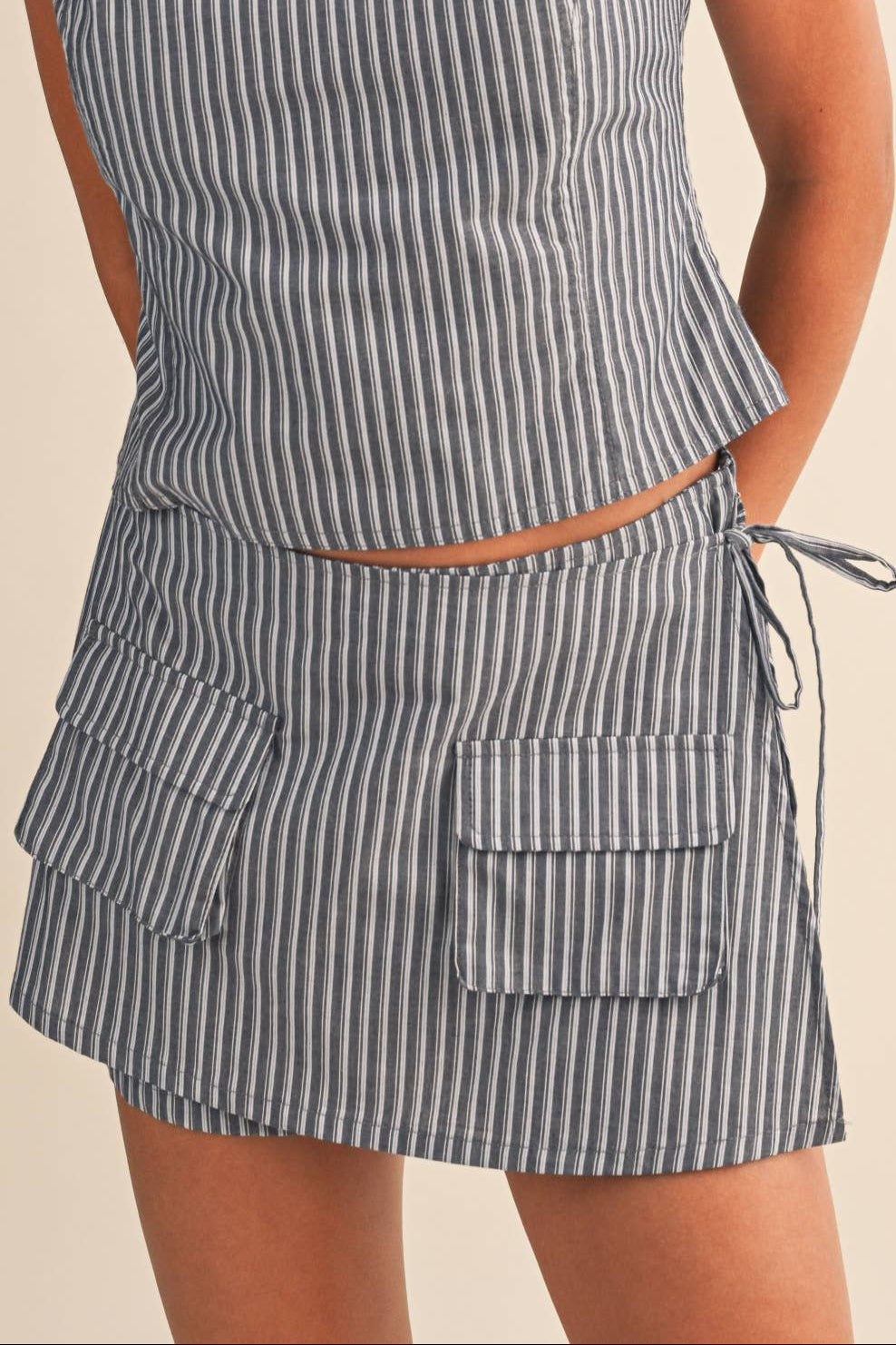 Woman wearing a gray striped skort with front pocket on a beige background