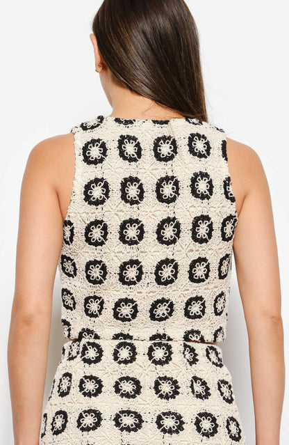 Woman wearing a sleeveless top with a black and white pattern against a white background