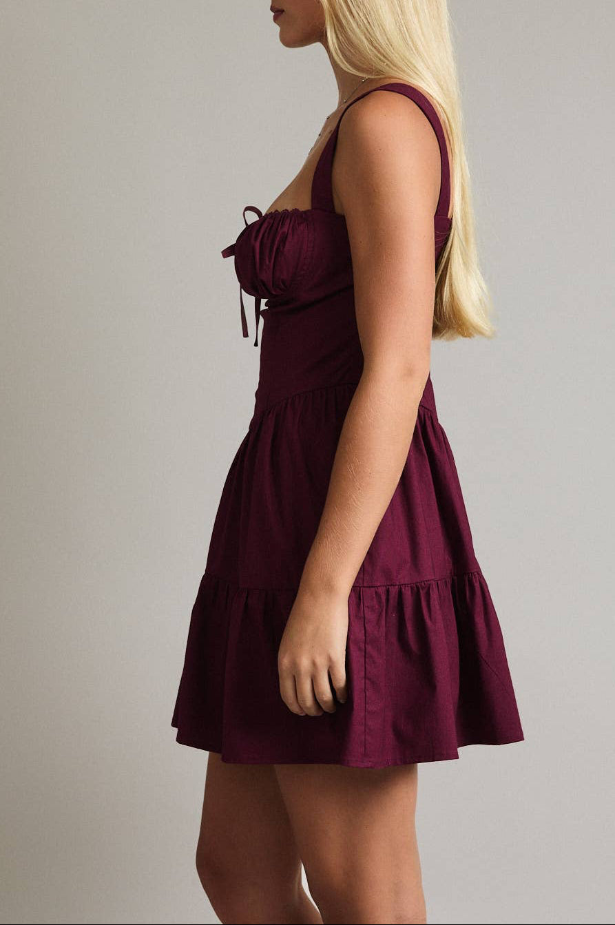 Woman wearing a burgundy dress against a plain background
