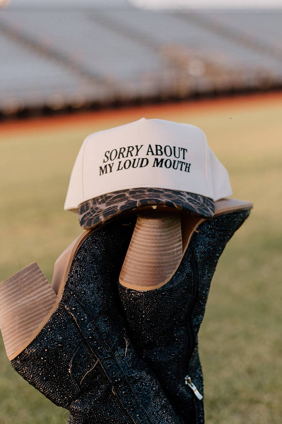 Cap with 'Sorry About My Loud Mouth' text on a blurred outdoor background