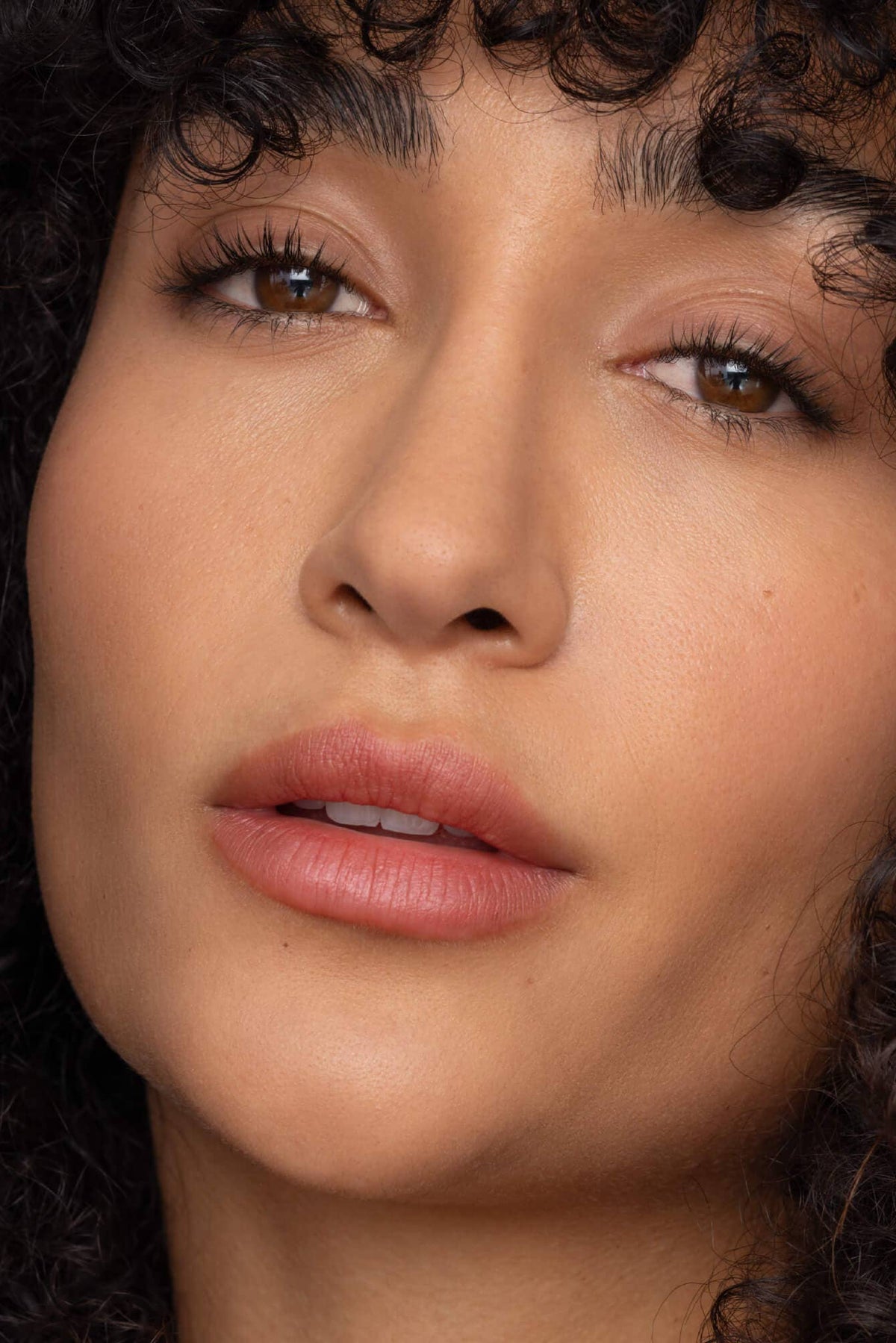 Close-up of a woman with curly hair and pink lipstick.