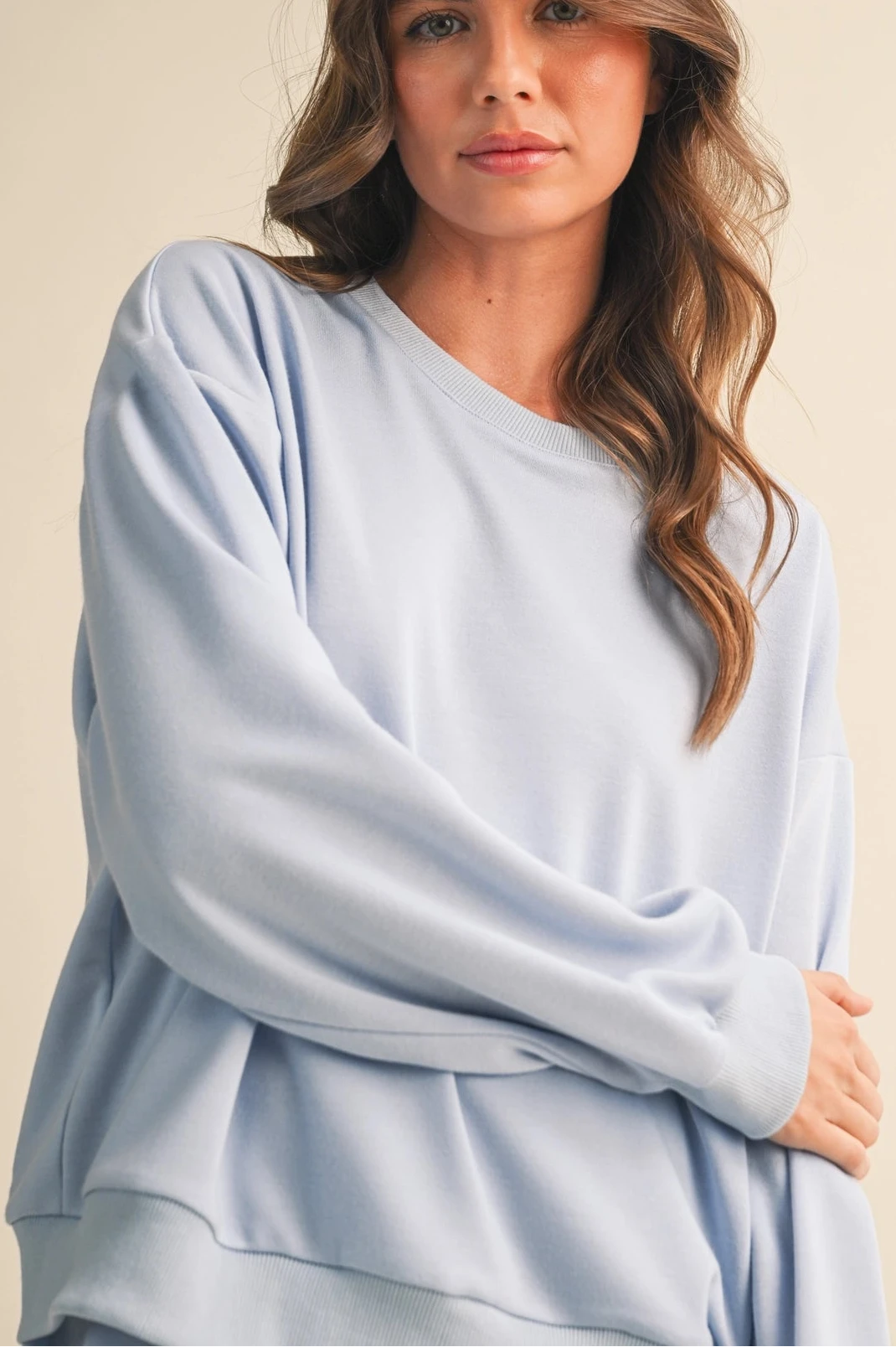 Woman wearing a light blue sweater against a beige background