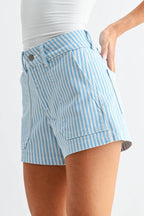 Woman wearing a white strapless top and light blue striped shorts on a white background