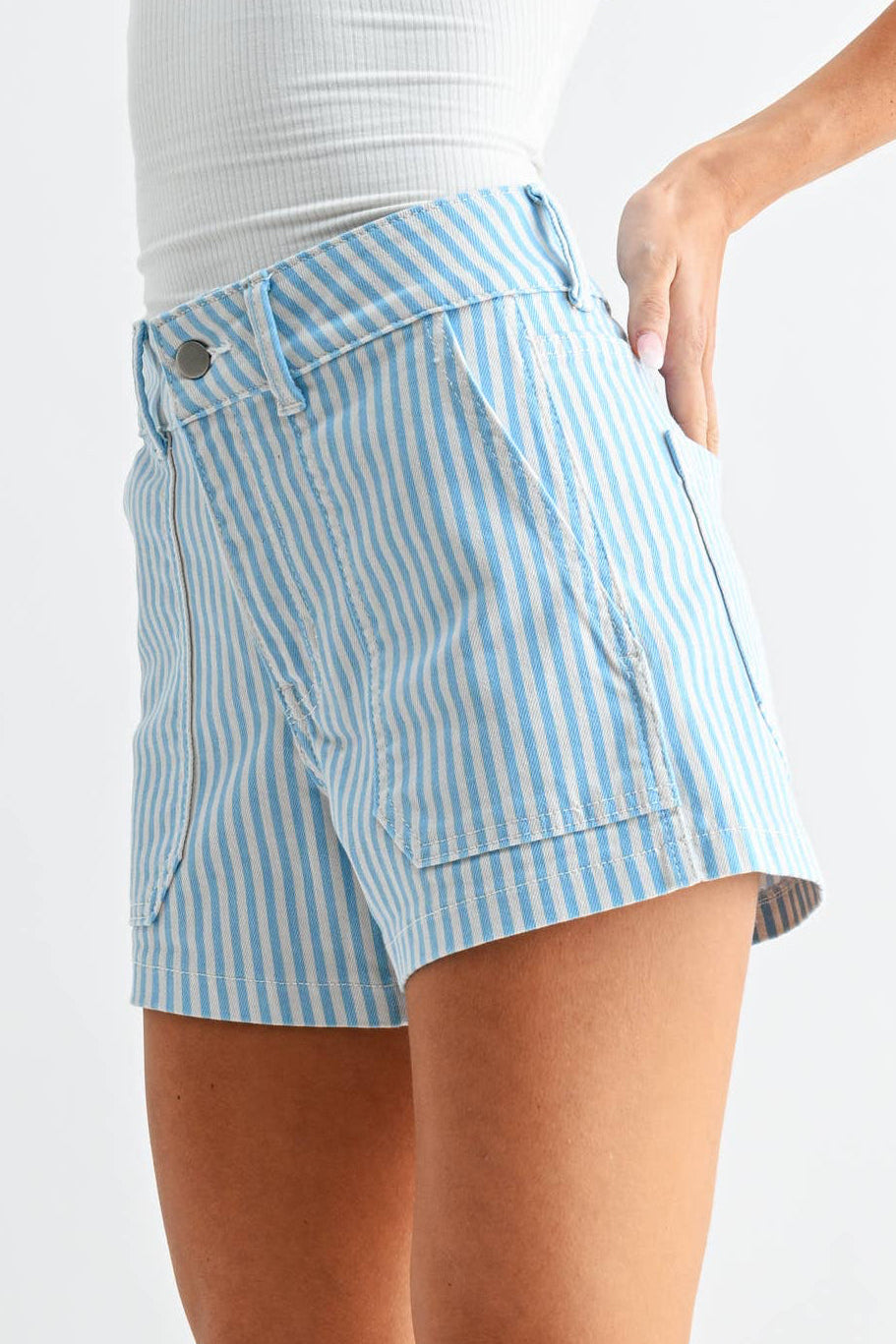 Woman wearing a white strapless top and light blue striped shorts on a white background