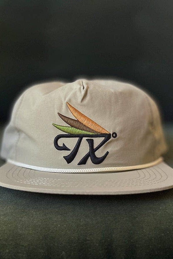 Beige cap with embroidered design on a dark surface