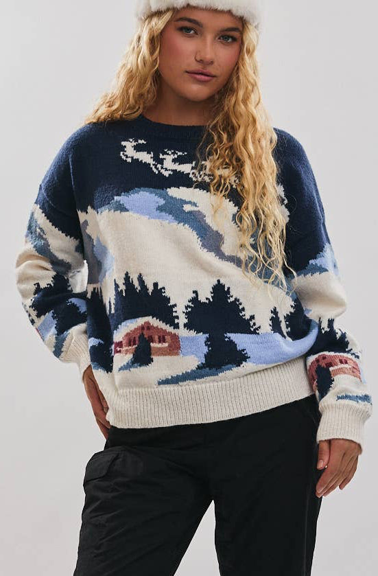 Person wearing a patterned sweater and black pants standing on a snowy surface.