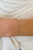 Silver bracelet on a person's wrist with a blurred background