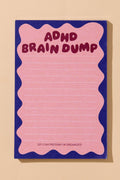 A pink lined notepad with a wavy pink border and a dark blue background, featuring the text 'ADHD BRAIN DUMP' in dark pink at the top and 'SO I CAN PRETEND I'M ORGANIZED' at the bottom, shown on a beige background.