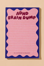A pink lined notepad with a wavy pink border and a dark blue background, featuring the text 'ADHD BRAIN DUMP' in dark pink at the top and 'SO I CAN PRETEND I'M ORGANIZED' at the bottom, shown on a beige background.