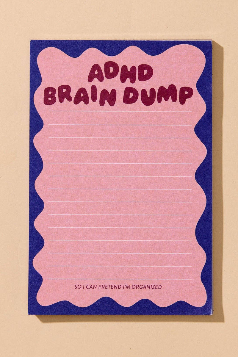 A pink lined notepad with a wavy pink border and a dark blue background, featuring the text 'ADHD BRAIN DUMP' in dark pink at the top and 'SO I CAN PRETEND I'M ORGANIZED' at the bottom, shown on a beige background.