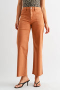 A woman modeling a sleeveless halter top with a black and white leopard print pattern and high-waisted, wide-leg cropped pants in a warm rust-orange color, paired with black heeled sandals, against a plain light gray studio background.