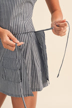 Person wearing a striped skort with a tie, holding a strap.