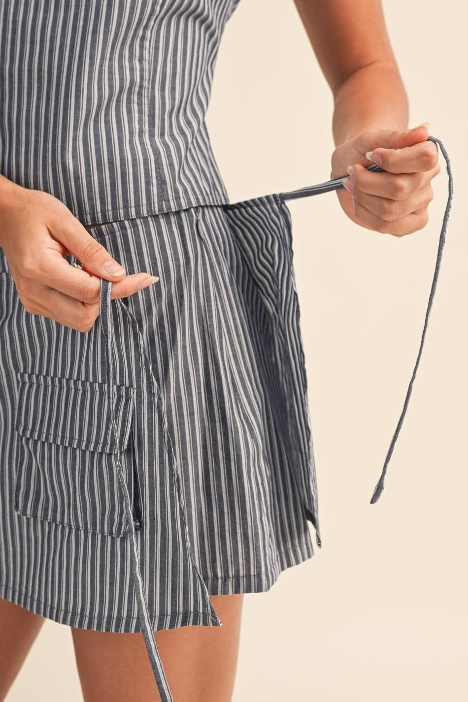 Person wearing a striped skort with a tie, holding a strap.