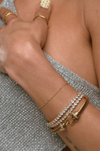 Close-up of a hand wearing gold rings and bracelets on a textured surface