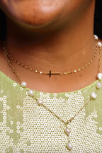 Close-up of a person wearing a gold necklace with pearl accents and a green sequined top.