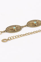 An antique bronze-toned metal chain bracelet featuring oval concho-style medallions with engraved western motifs and small turquoise accents, shown on a plain white background.