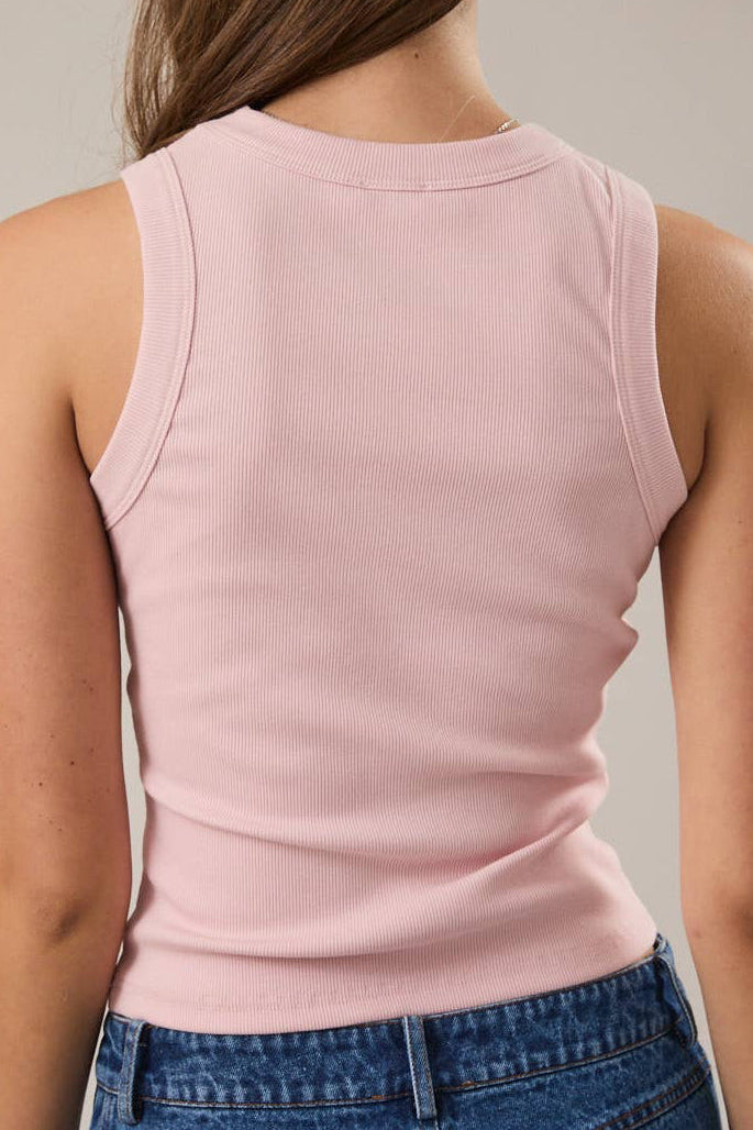 Person wearing a pink sleeveless top and blue jeans against a neutral background