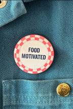 Button with 'FOOD MOTIVATED' text on a denim jacket