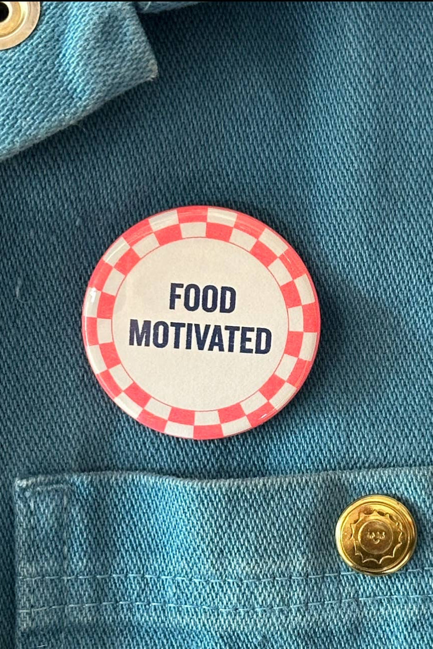 Button with 'FOOD MOTIVATED' text on a denim jacket