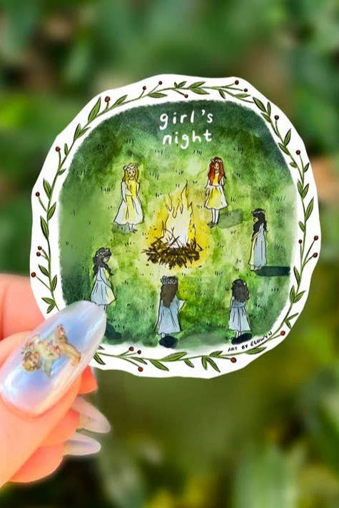 Decorative plate with illustration of 'girl's night' and people around a campfire, held against a green leafy background.